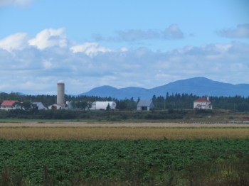 Flat farmland on this side, with a backdrop of hills on the other side